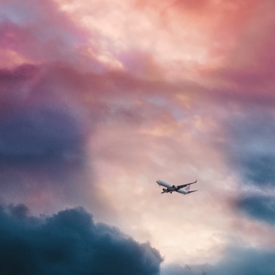 View of passenger plane flying through thick, pink clouds